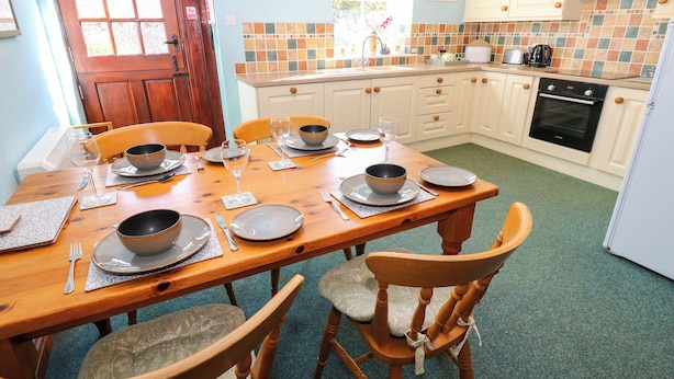 Un comedor con una mesa de madera dispuesta para cuatro personas, rodeada de sillas.