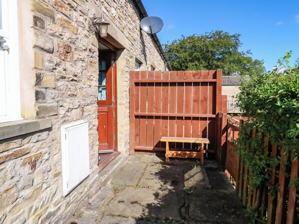A stone building with a wooden door, a satellite dish, and a wooden bench outside. - Barnbrook (Leyburn)