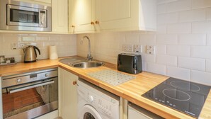 A modern kitchen with stainless steel appliances, a built-in oven, a microwave, a sink, a toaster, and a dishwasher. - Kirk Cottage (Kelso)