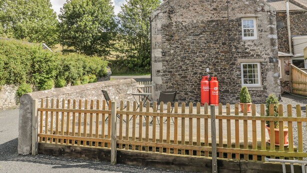 A stone building with a wooden fence in front. - Kirk Cottage (Kelso)
