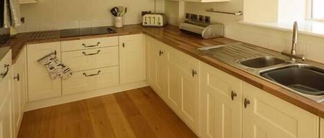 A kitchen with wooden flooring, white cabinets, a toaster, and a sink.