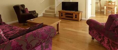 A living room with a sofa, a chair, a coffee table, and a TV on a stand.