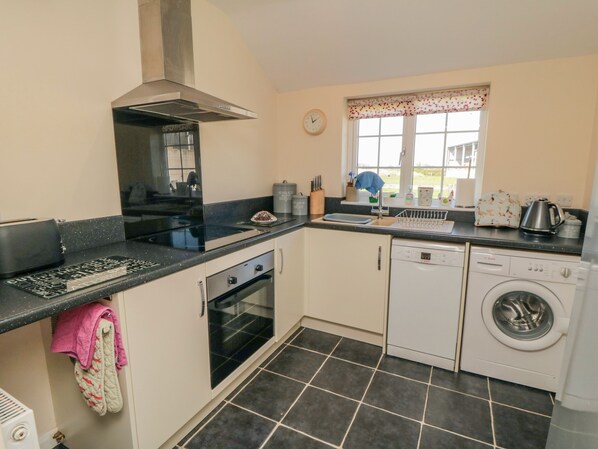 A compact kitchen with a stove, oven, dishwasher, and washing machine. - Bellafax Cottage (Malton)
