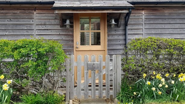 A wooden cottage with a wooden door and a small porch. - Bicton Lodge (Craven Arms)