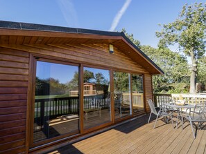 Une cabane en bois dotée d’une terrasse, de grandes portes-fenêtres coulissantes et de mobilier d’extérieur.