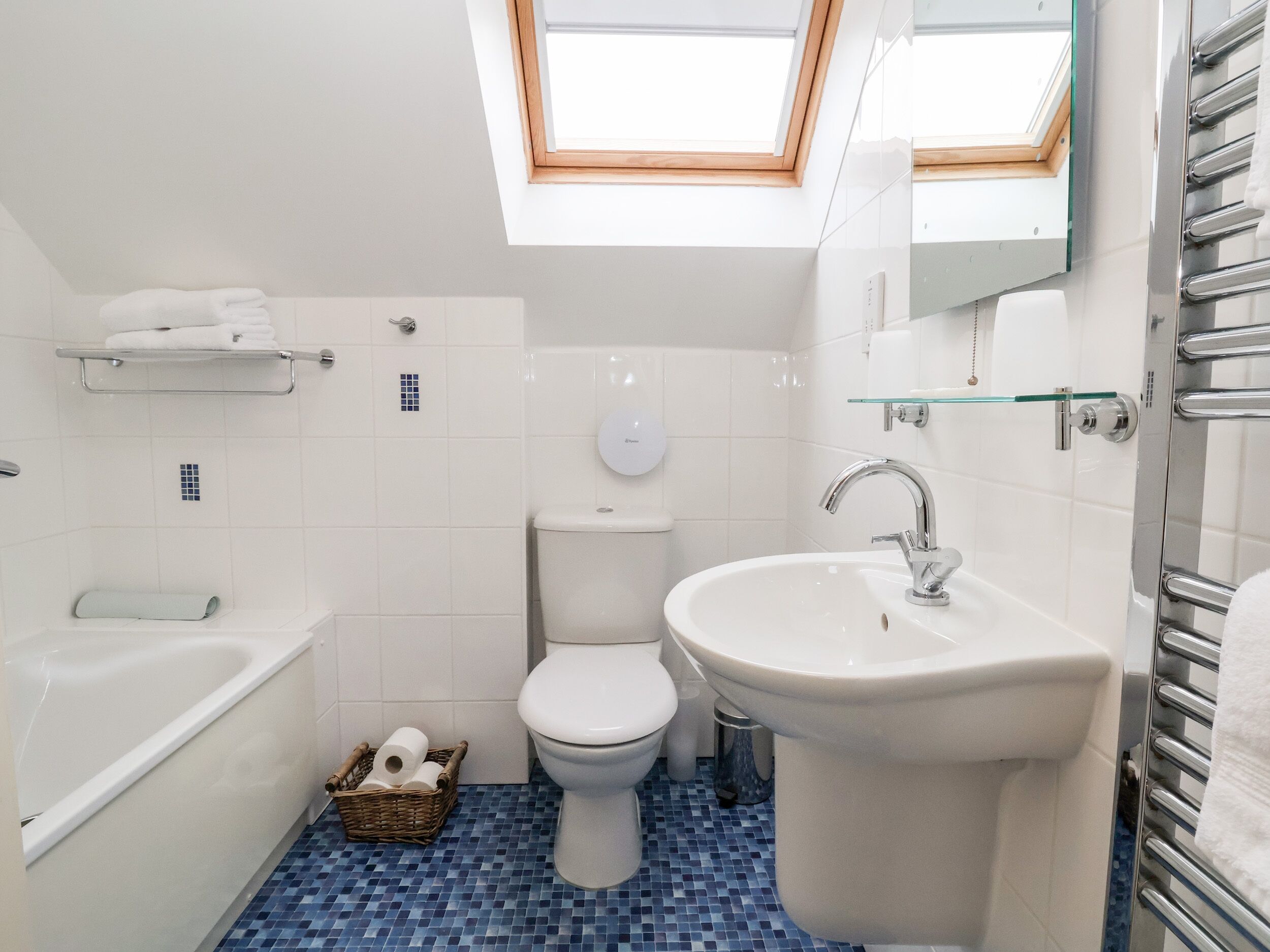 Un baño moderno con tragaluz, bañera, inodoro y lavabo.
