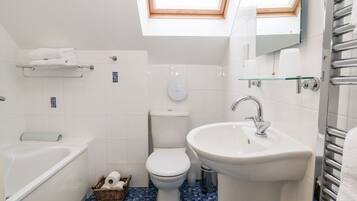 Un baño moderno con tragaluz, bañera, inodoro y lavabo.