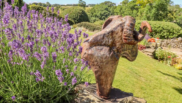 A garden with a sculpture of an elephant on a stone base, surrounded by lavender plants. - 1 Bridge End &amp; Garden (Skipton)