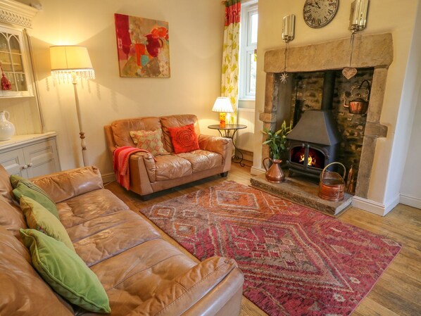 Un salon chaleureux avec un canapé en cuir, un tapis à motifs, une cheminée et un tableau accroché au mur.