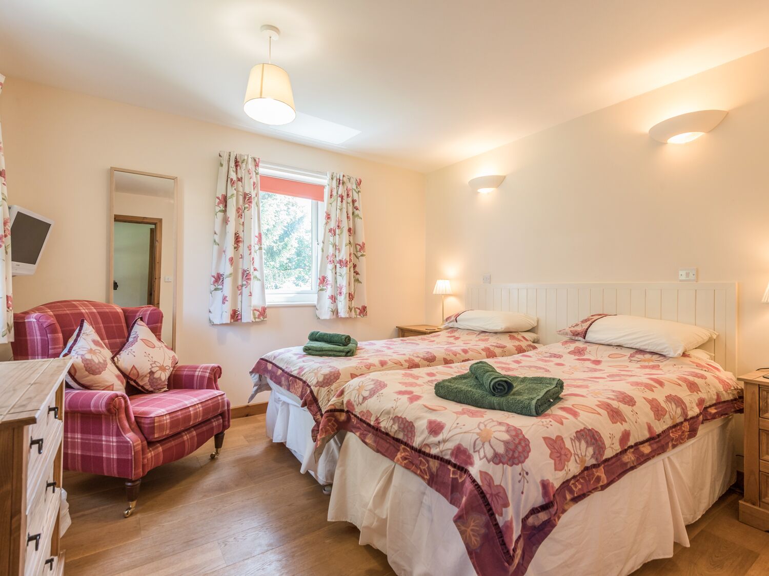 A bedroom with a bed, a chair, a desk, and a window with curtains.
