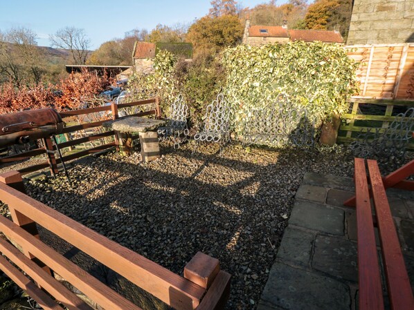 A garden with a wooden bench, a metal fence, and a stone wall. - The Old Cart House (York)