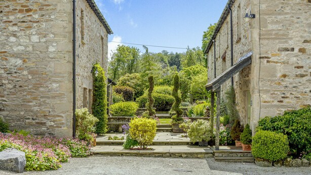 A stone building with a garden leading to a wooden door. - Pickle Barn (Carnforth)