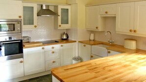 A kitchen with white cabinets, a wooden countertop, a stainless steel oven, and a tiled backsplash.