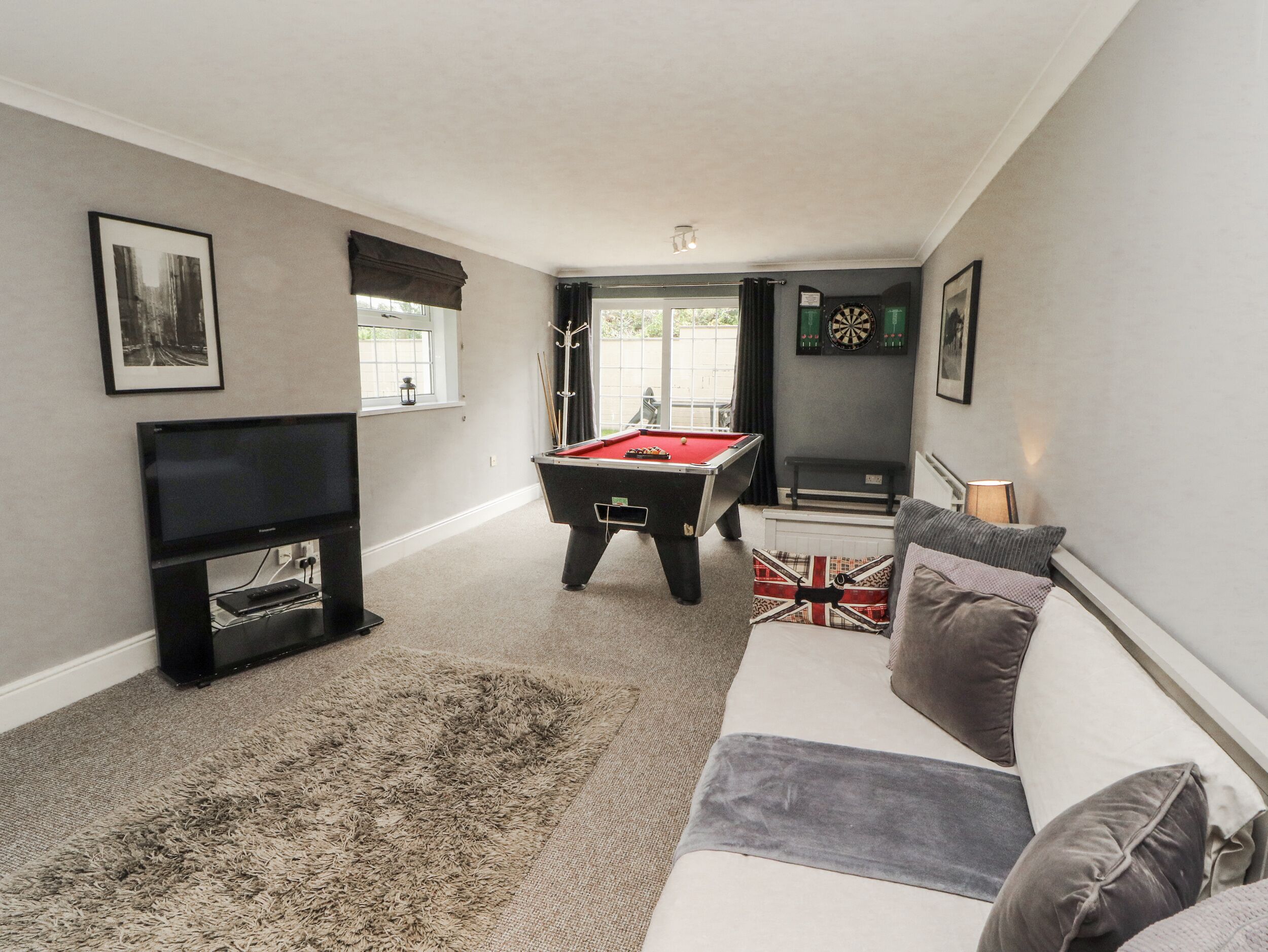 A living room with a pool table, a television, and a couch.