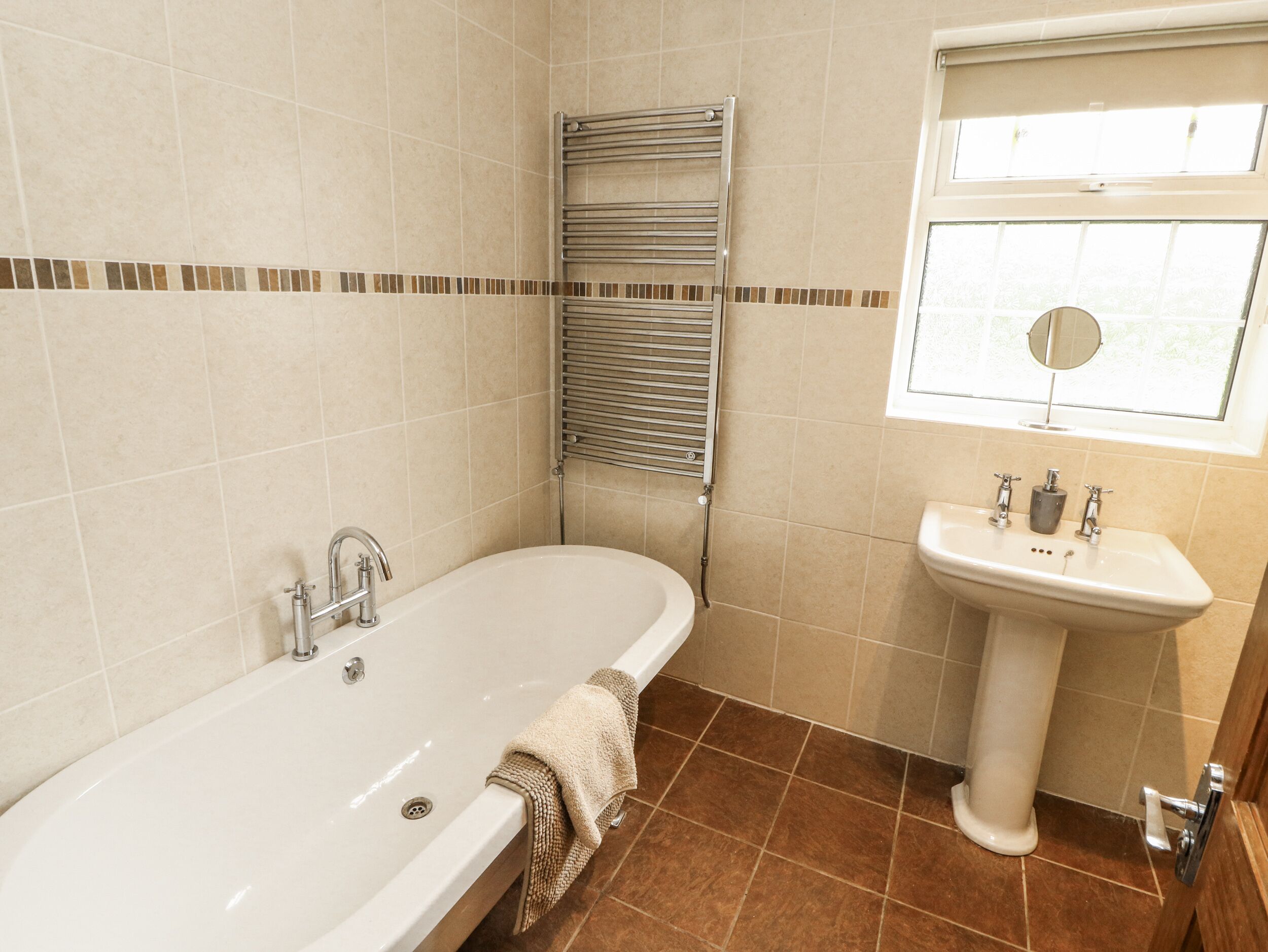 A bathroom with a bathtub, a sink, and a window.