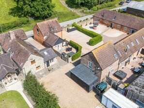 An aerial view of a residential area with multiple houses, a gravel driveway, and a small parking area.