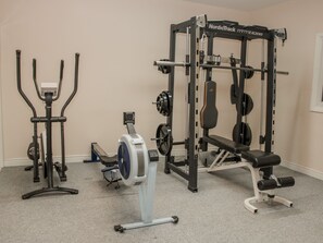 A home gym with a NordicTrack machine, a stationary bike, and a squat rack.
