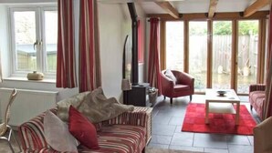 A cozy living room with a striped sofa, a red armchair, and a coffee table. - Hour Cottage (Cheltenham)