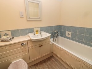Bathroom features a classic sink, mirror, and bathtub with modern faucet, complemented by blue tile walls and a towel rack.