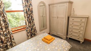Une chambre à coucher avec un lit, une armoire, une commode et une fenêtre avec des rideaux.