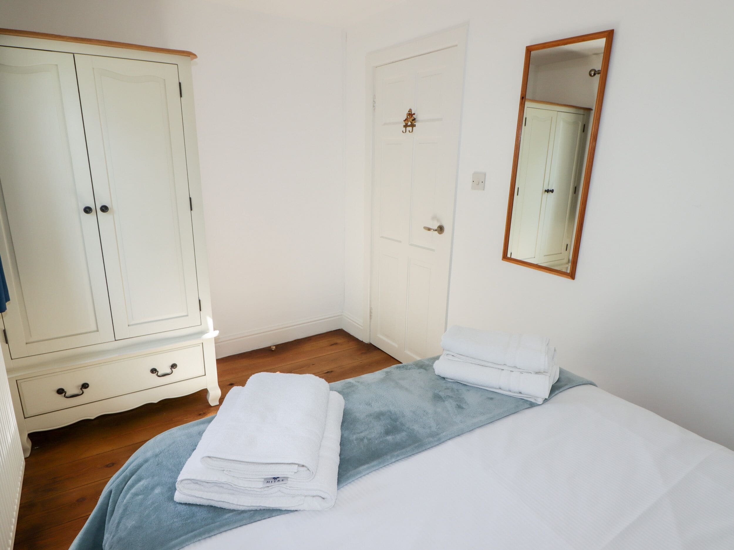 Un dormitorio con cama, armario, puerta y espejo.