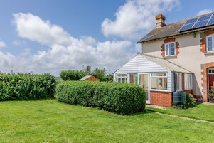 Uma casa com estufa, jardim e painéis solares no telhado.