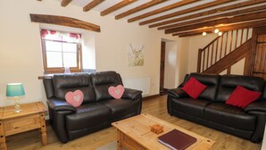 Ein Wohnzimmer mit zwei Ledersofas, einem Holztisch, einer Lampe und einer Treppe.