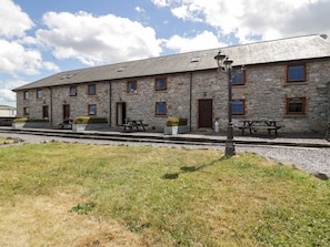 A stone building with multiple windows and doors, outdoor seating, and a lamp post.