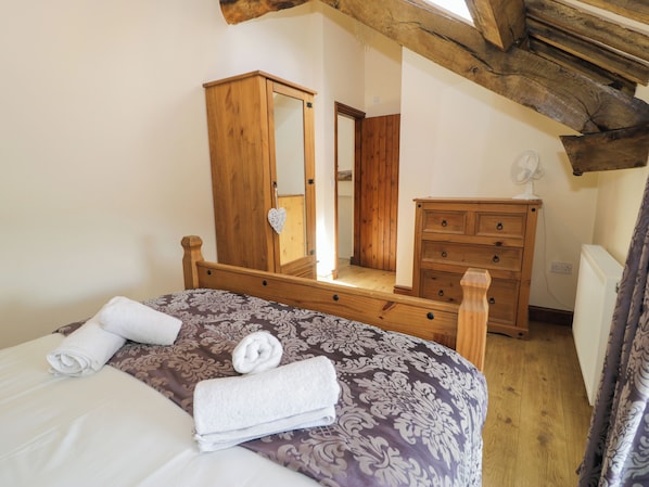A bedroom with a wooden bed, a dresser, a mirror, and a ceiling fan.