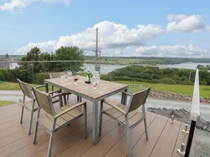 A wooden deck with a table and chairs overlooking a river. - Penrallt Cottage (Y Felinheli)