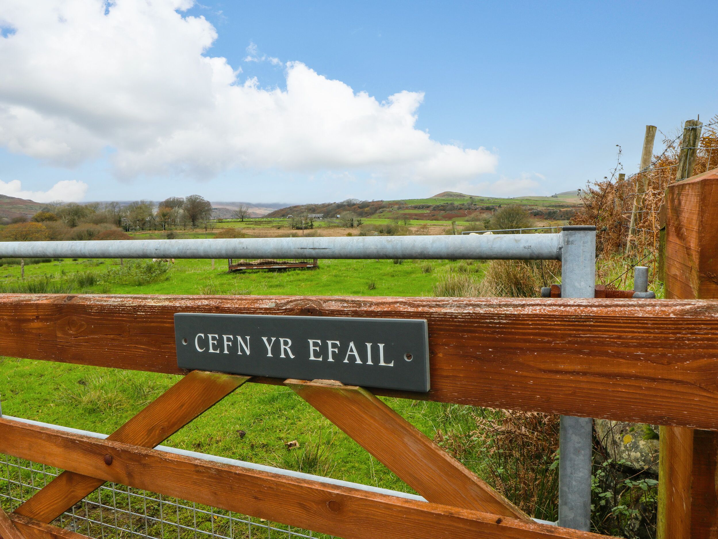 A wooden gate with a sign that reads "CEFNR YR EFAL".