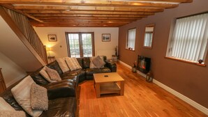 A cozy living room with a leather sofa, wooden coffee table, and a fireplace. - Cefn-yr-efail (Garndolbenmaen)