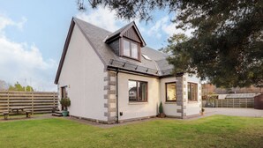 A two-story house with a sloped roof, large windows, and a well-maintained lawn.