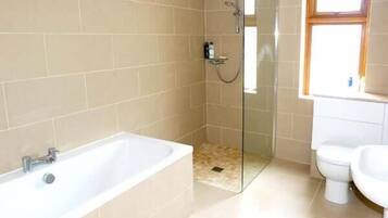 A bathroom with a glass-enclosed shower, a white bathtub, and a toilet.