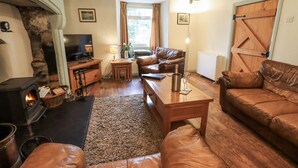 A cozy living room with a fireplace, leather sofas, a wooden coffee table, and a television. - Harber Scar (Settle)