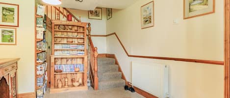 Una escalera con barandilla de madera, escalones alfombrados y una lámpara colgante roja.