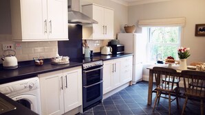 A kitchen with white cabinets, a black countertop, a stove, and a dishwasher. - West House (Barnard Castle)
