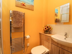 A bathroom with a towel rack, toilet, sink, and a mirror with a starfish decoration. - Marys House (Acharacle)
