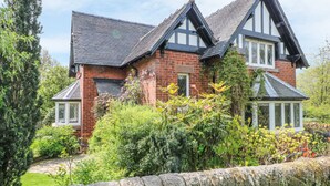 A large, two-story house with a brick exterior and a gabled roof. - Gun End Cottage (Macclesfield)