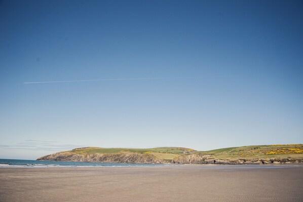 Enjoy a serene coastal escape with breathtaking views of the open beach and rolling hillside.