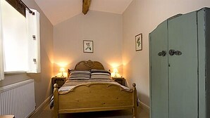 Ein Schlafzimmer mit einem hölzernen Bett, zwei Nachttischlampen, einer Heizung und einem Kleiderschrank.