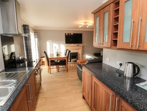 Enjoy cooking in the well-equipped kitchen with a granite countertop, wooden cabinetry, and stainless steel range hood.