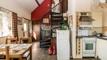 Una cocina con estufa, refrigerador y una escalera de caracol.