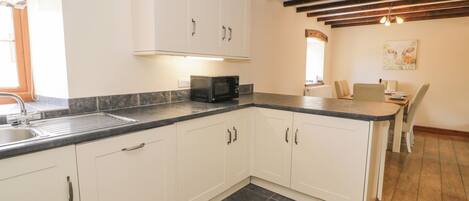 A kitchen with white cabinets, a black countertop, and a tiled floor.