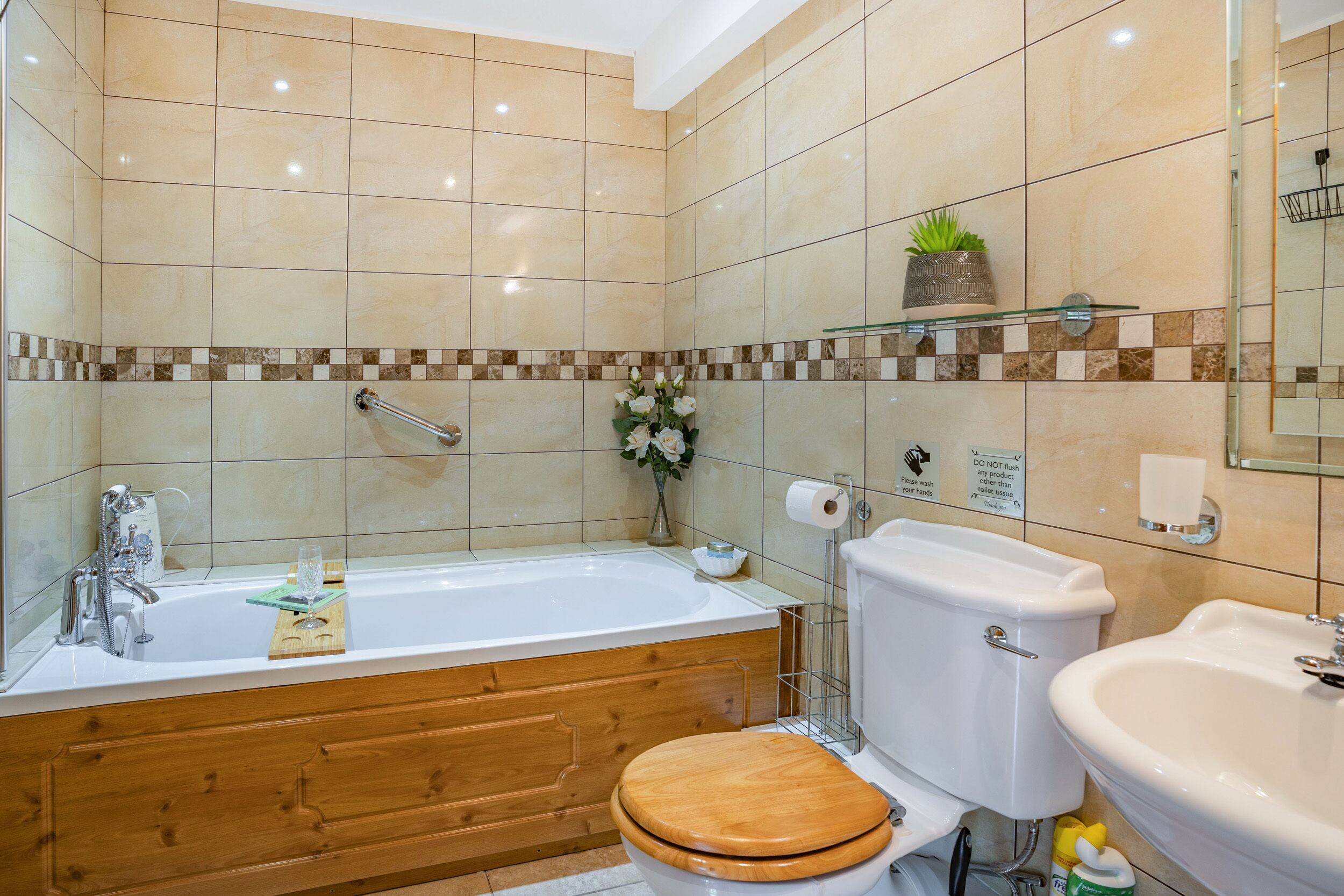 Un baño con bañera, inodoro, lavabo y tocador de madera.