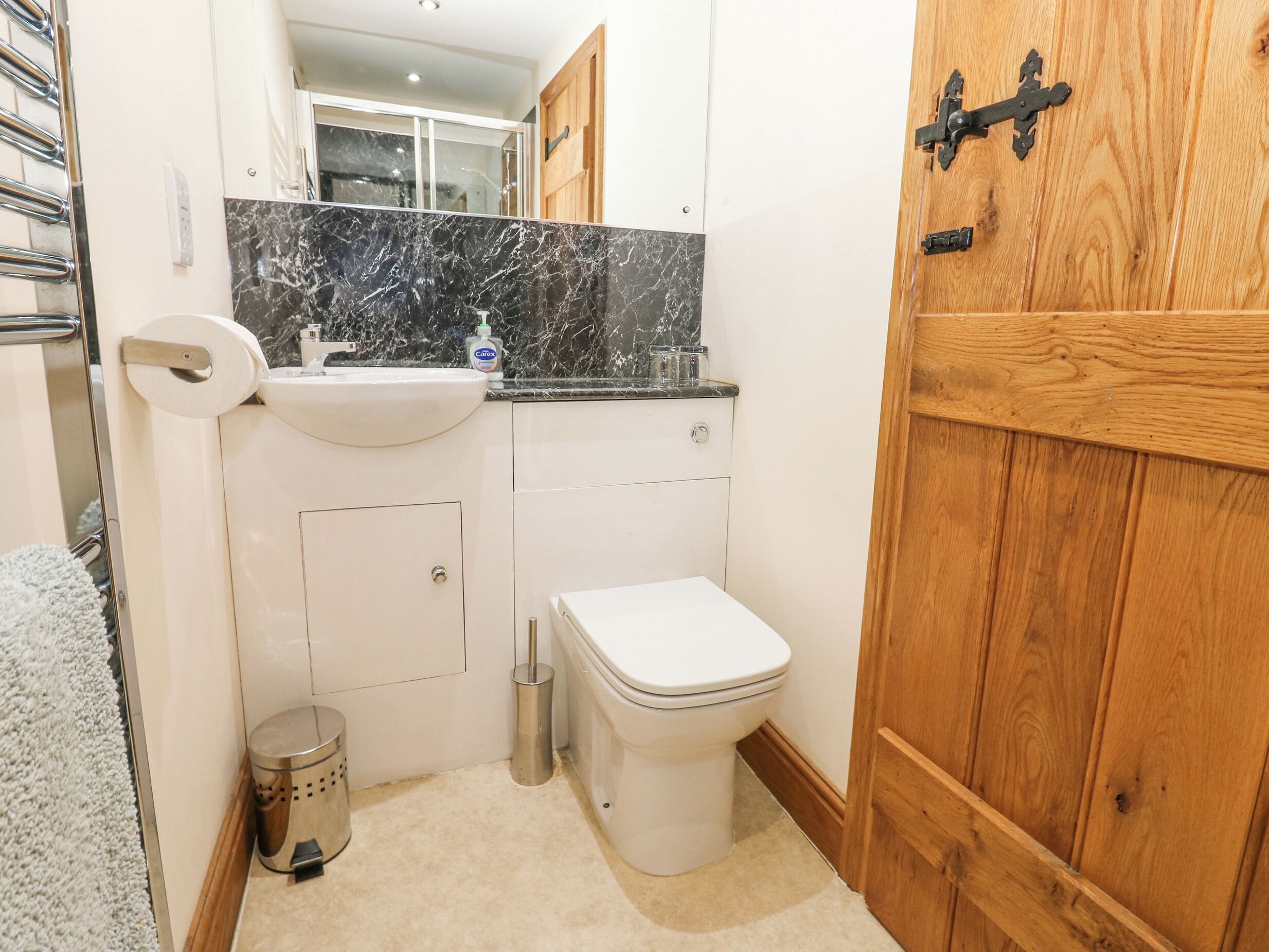 A compact bathroom with a white sink, toilet, and a mirror above the sink.