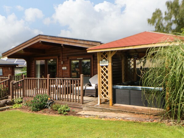 A wooden cabin with a fenced deck, a hot tub, and a sign welcoming visitors to Yorkshire. - Cornfield (Northallerton)