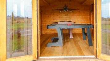 Una habitación con piso de madera, mesa de billar y un reloj en la pared.