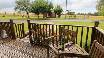 A wooden deck with a table and chairs, a bottle, and a glass.