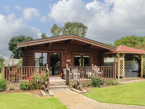 A wooden lodge with a porch, a covered carport, and a sign indicating 'Careful Lodge'. - Cornfield (Northallerton)